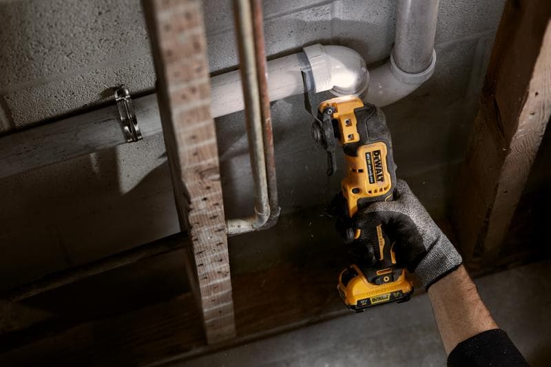 Person schneidet mit einem kabellosen DEWALT Oszillationswerkzeug ein Rohr an einer Betonwand.